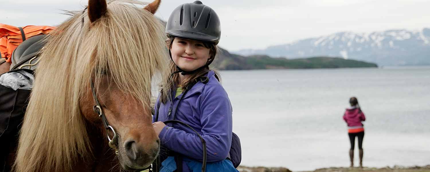 Ridpaus med islandshäst och barn vid sjön Thingvallavatn