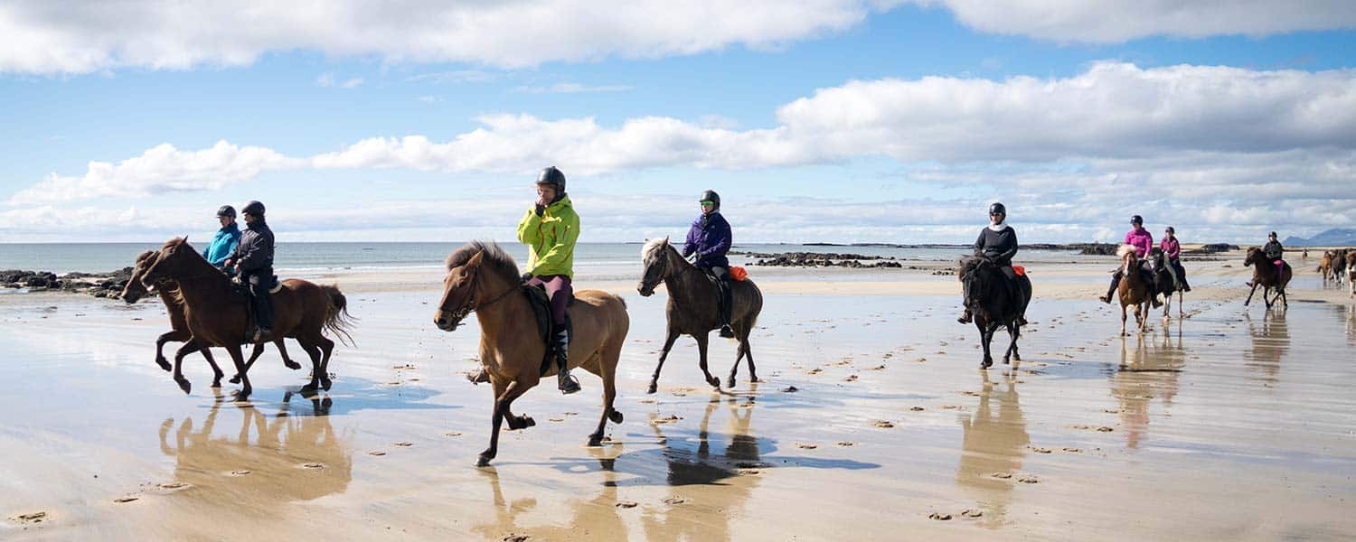 Rider längs gyllene sandstränd intill det blå havet